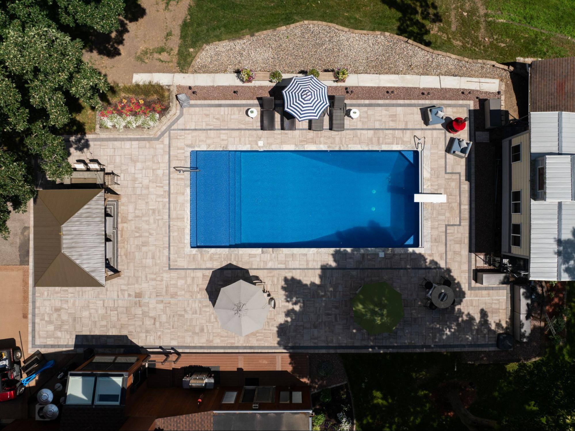 aerial shot of an in-ground pool surrounded by a converted caboose, outdoor living room, and pool chairs covered by umbrellas.