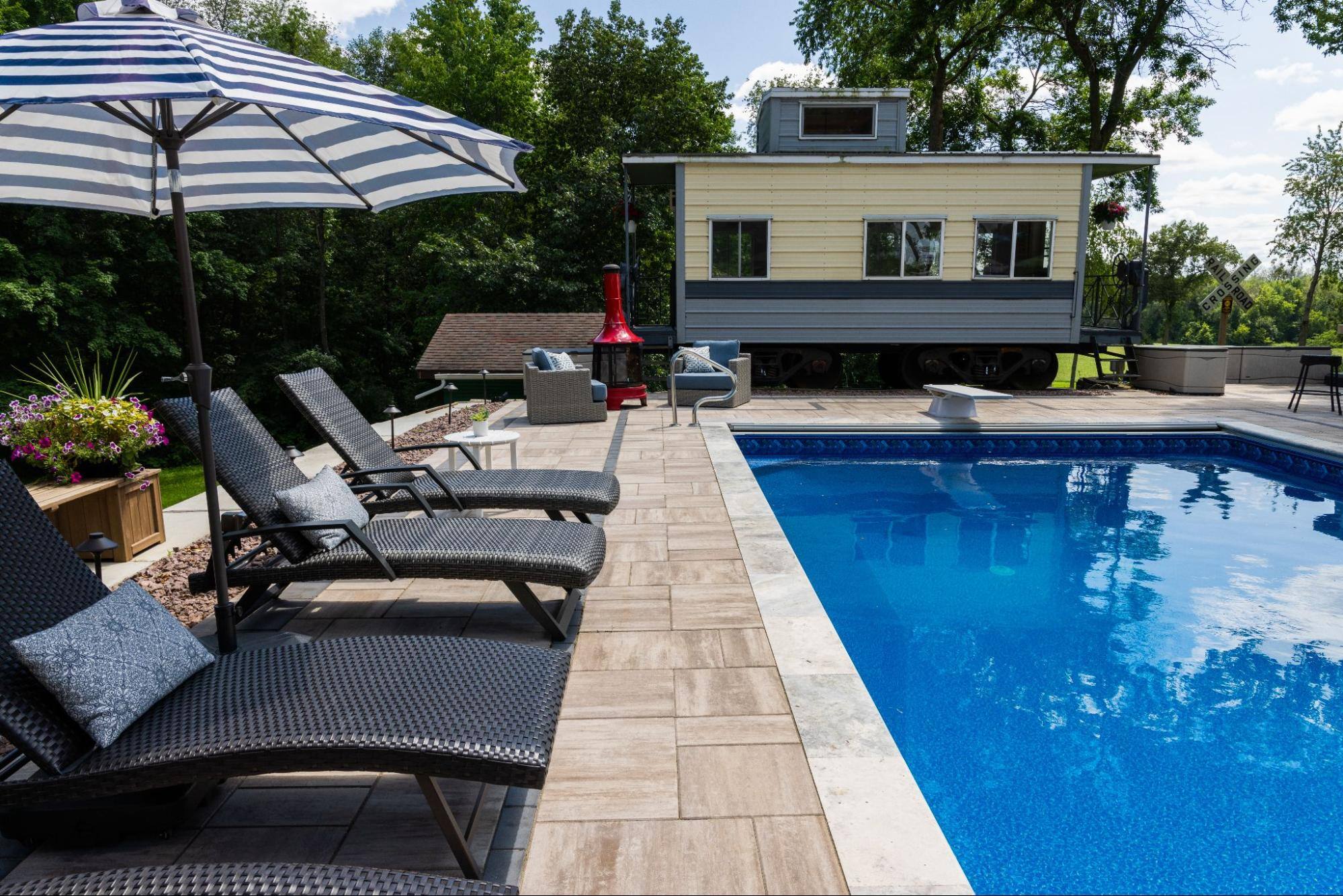 in-ground pool. nearby is a caboose converted into a poolhouse.