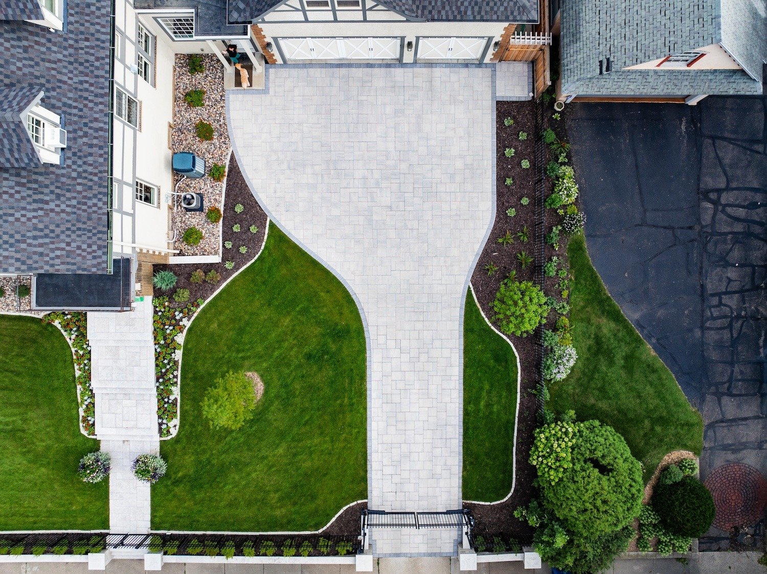 aerial shot of a driveway with surrounding pavers and green grass.