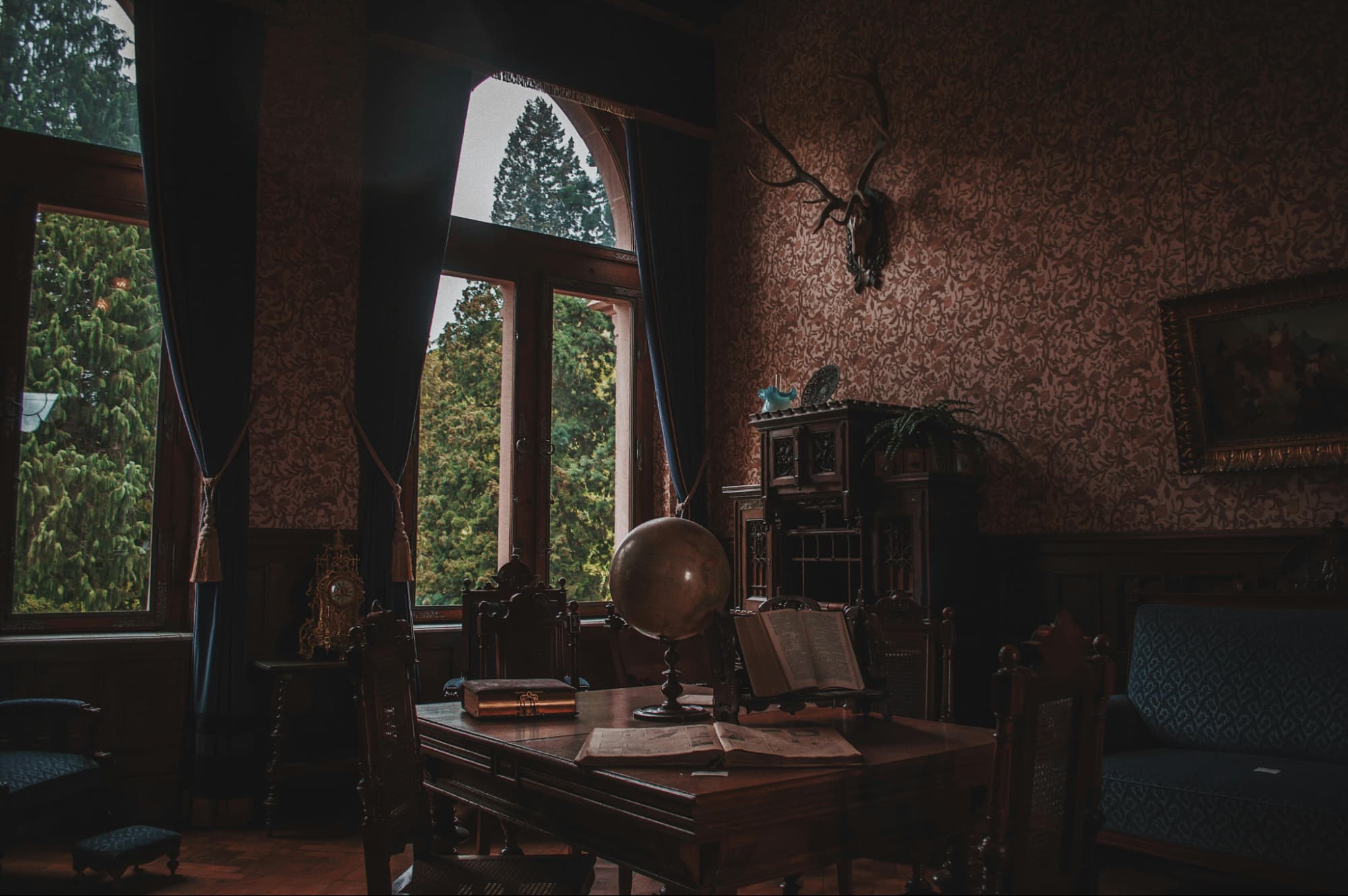 interior of a home study in dark academia style: moody, dark wallpaper, dark wooden furniture, classic decor.