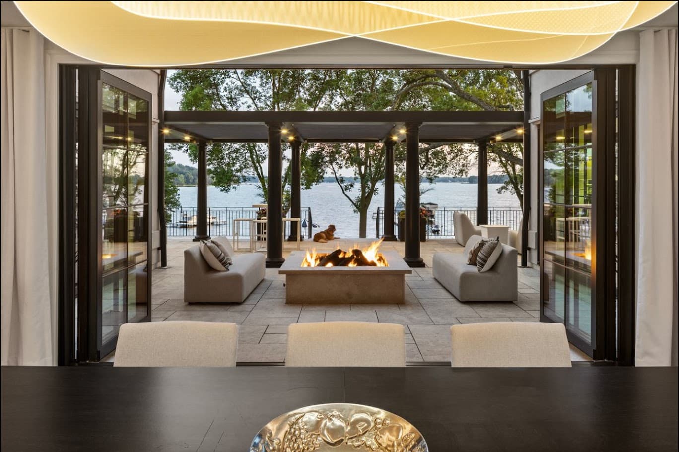 indoor/outdoor area with large folding doors. the interior dining area leads out into an outdoor gathering area with a modern fire pit.
