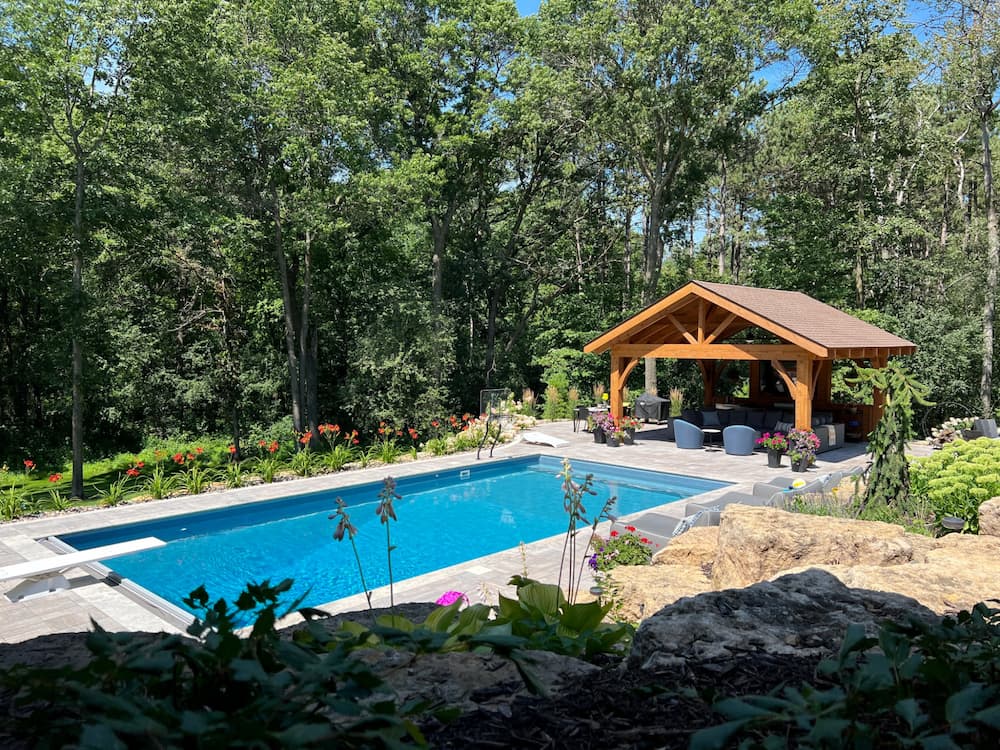 a backyard with a pool, gazebo, and garden