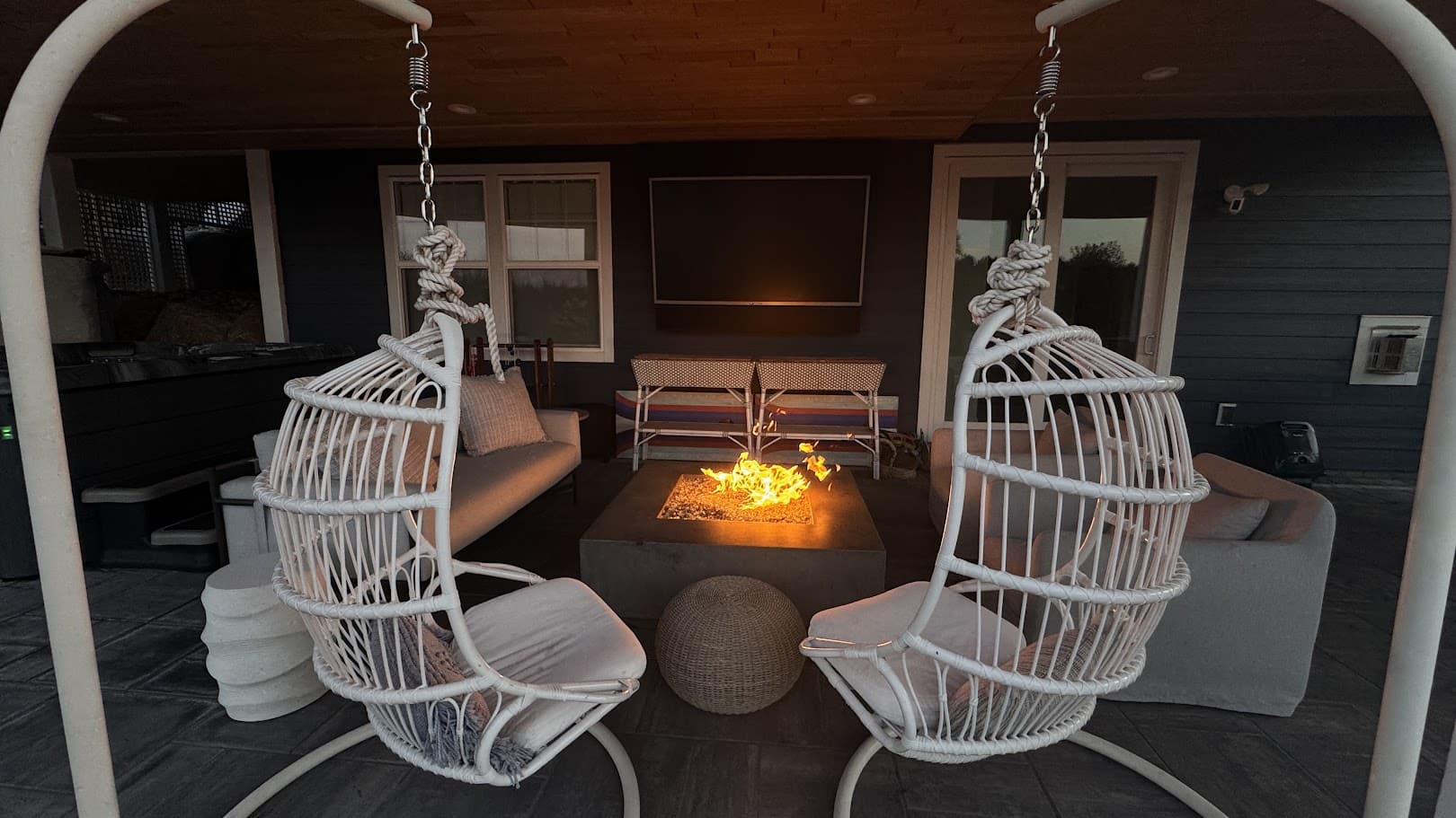 two white wicker hanging chairs around a fire pit