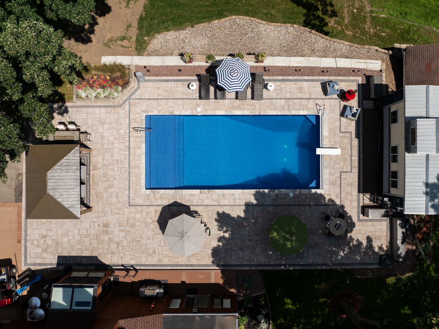 a backyard with a beautiful in-ground pool surrounded by pavers.