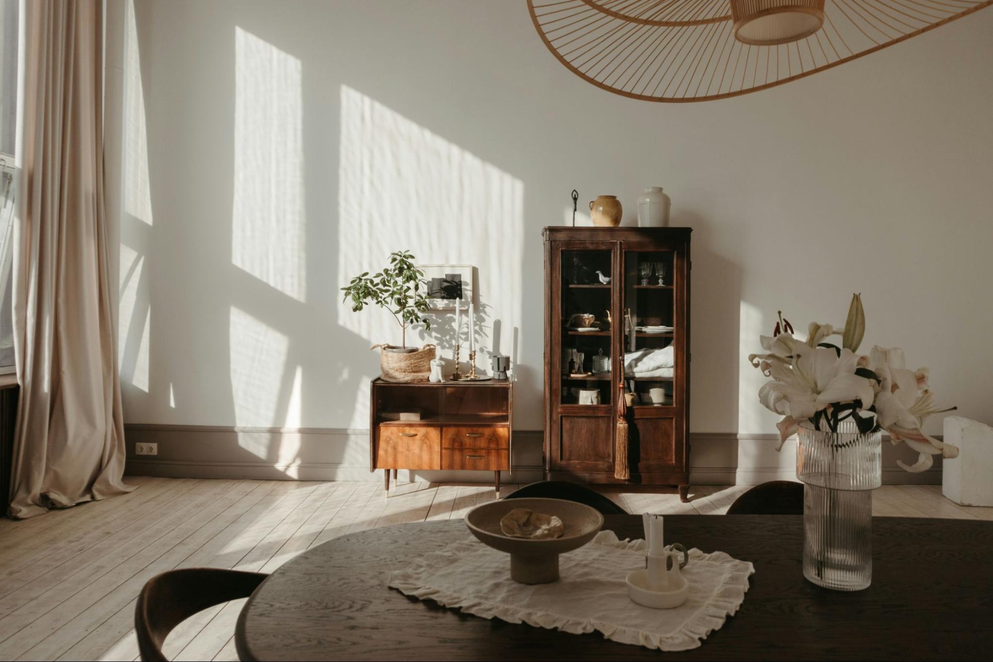 a zen minimalist living room. sparse colors and decor. the few pieces of furniture have a natural wood finish. Plants serve as decor.