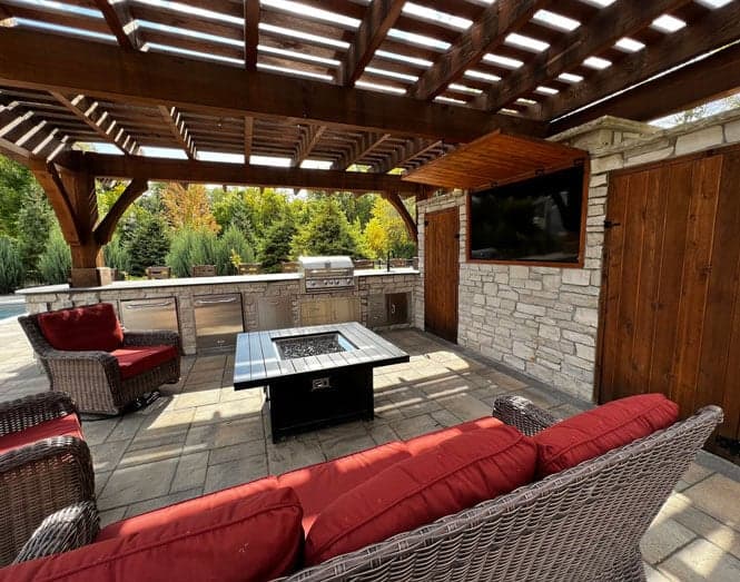 an outdoor cooking and dining area with a large grill, fire table, and ample seating.