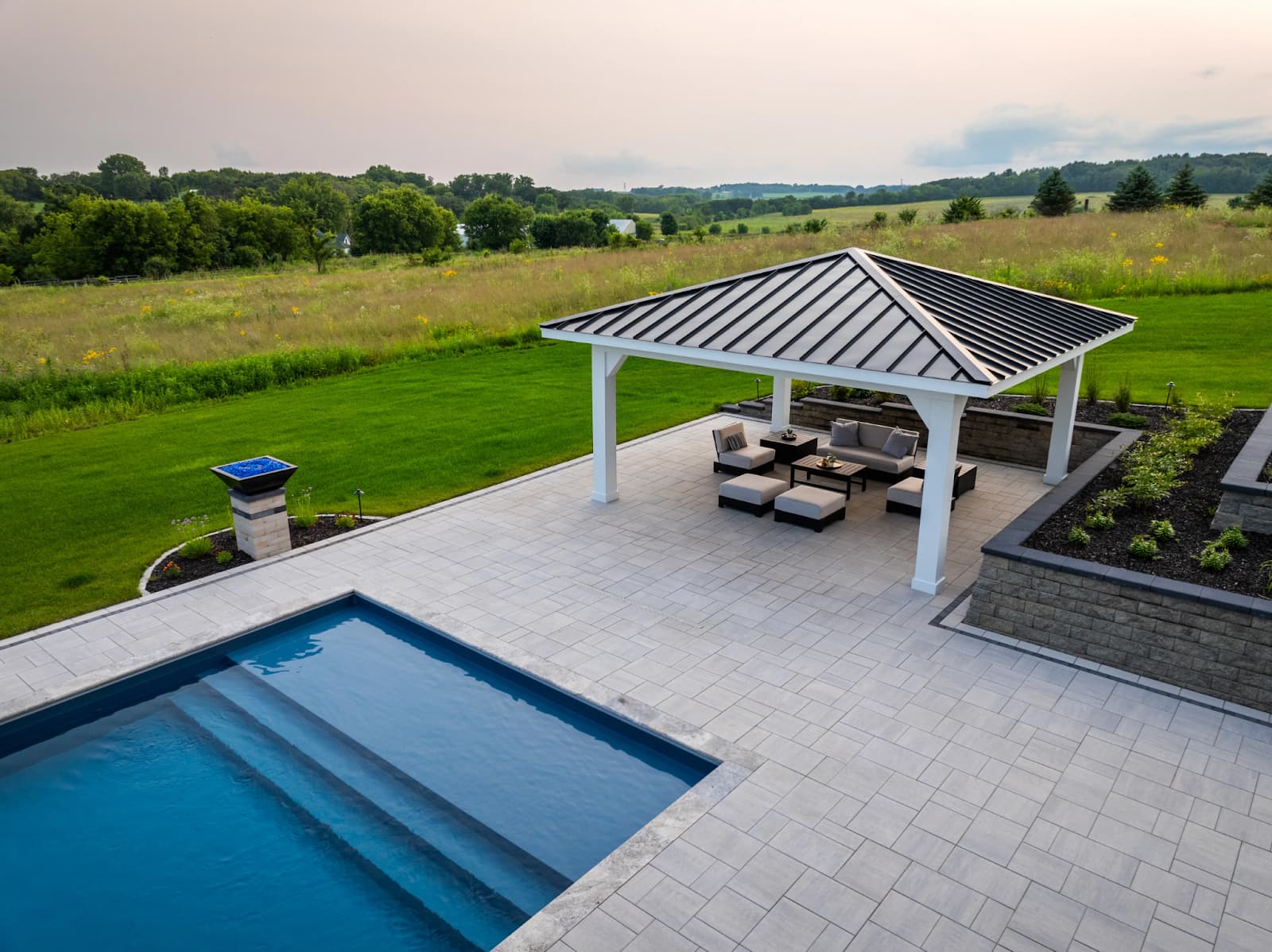 a pavilion covering an outdoor living room next to a pool.