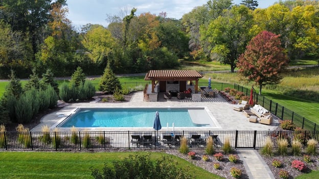 a pergola covering a seating area next to an in-ground pool