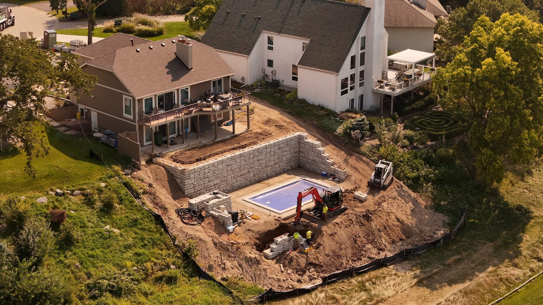 a sloped backyard with an in-ground pool and retaining walls