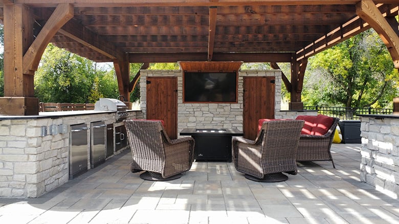 interior of an outdoor kitchen and living room combo with view into entertainment area.