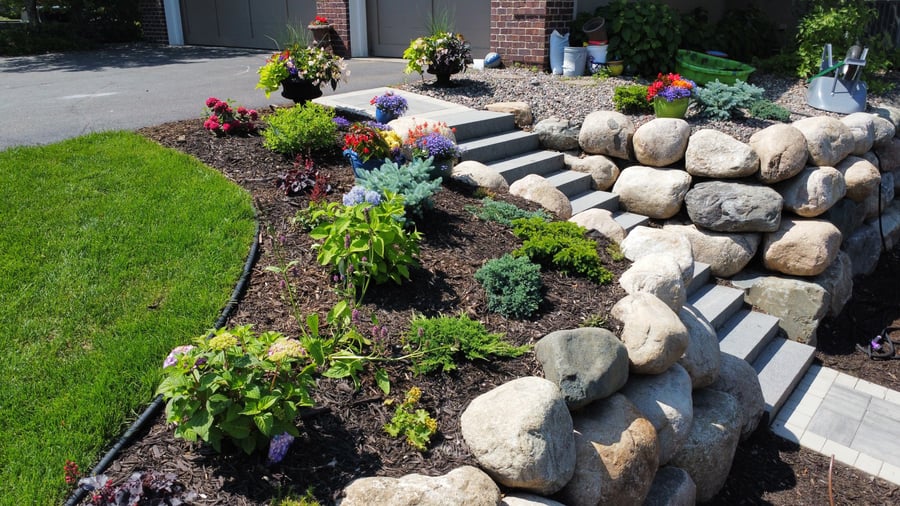 a garden area surrounding a pathway from a driveway to a backyard