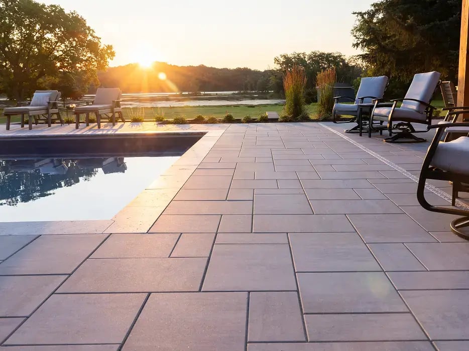Pavers around a pool with the sunsetting in the background