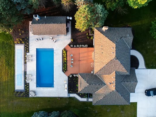 Overhead of large home with deck, poolhouse, pool and white pavers