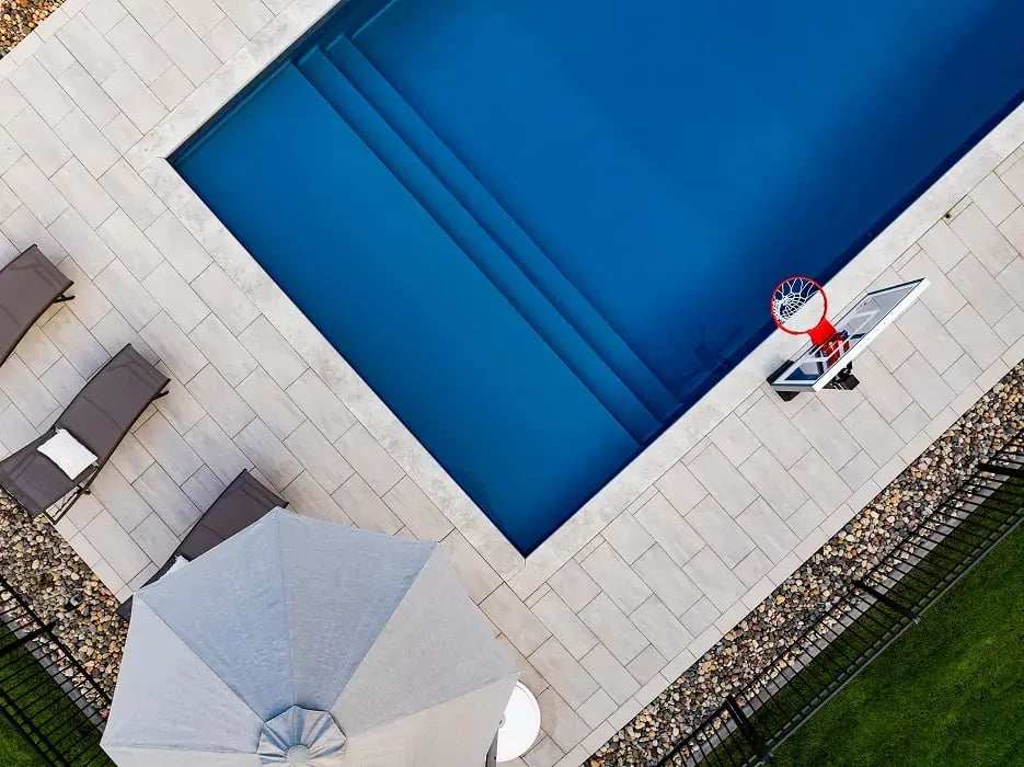 Overhead of a deep blue pool with a white pool deck surrounding