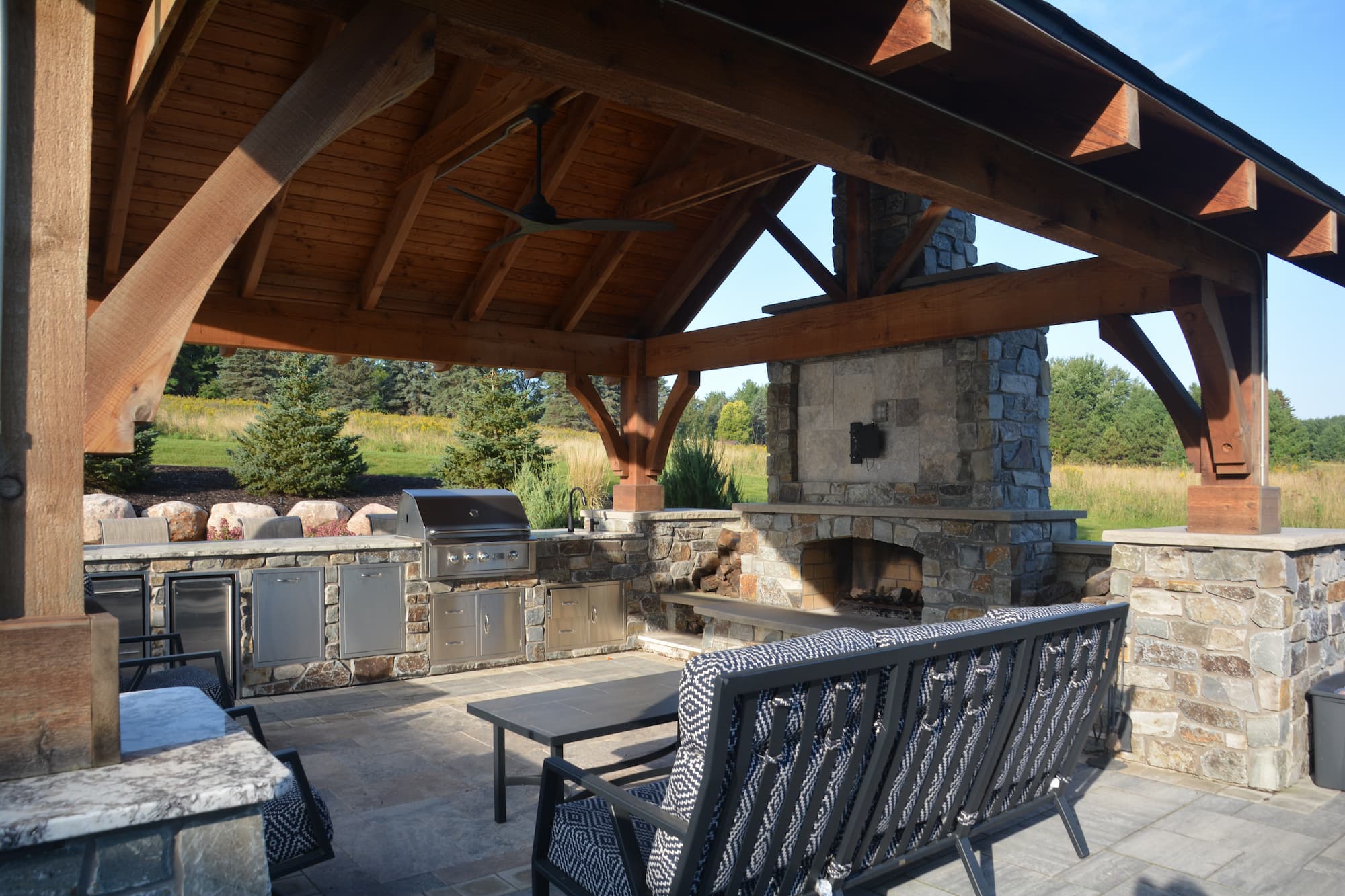 an outdoor kitchen with integrated fireplace, grill, fridge, and dishwasher.