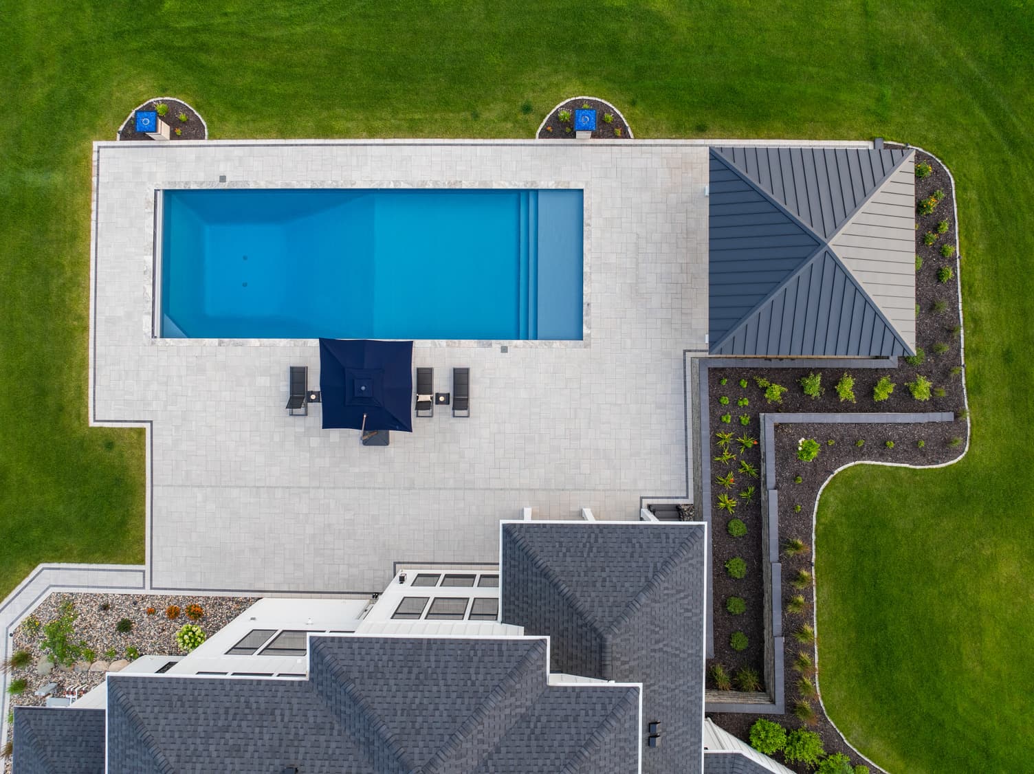 an aerial shot of a pool surrounded by large paver