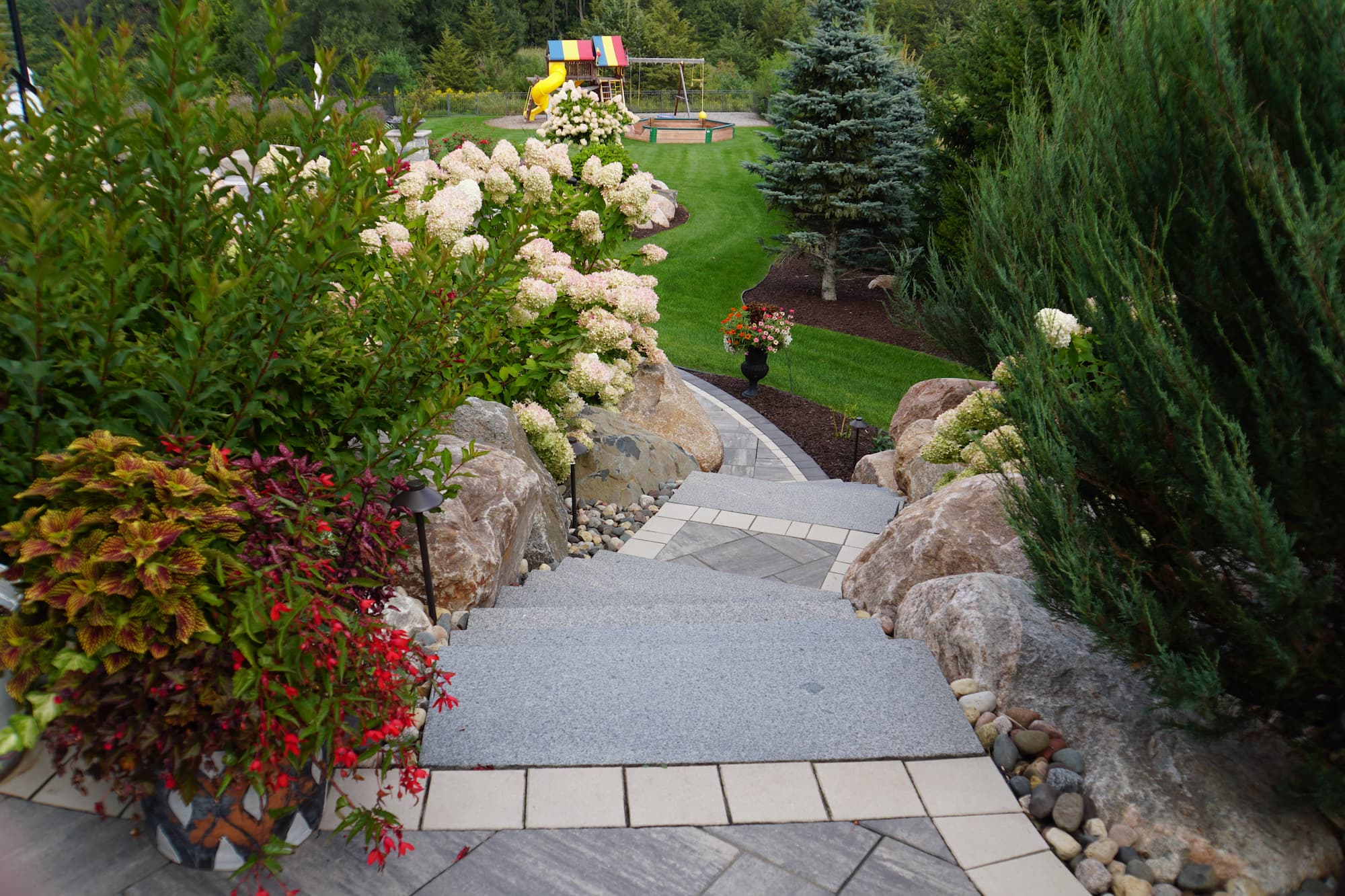 a view down an outdoor staircase, with retaining walls on either side and gardens