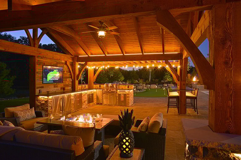 covered deck with ambient lighting, fire table, and outdoor kitchen with comfy seating