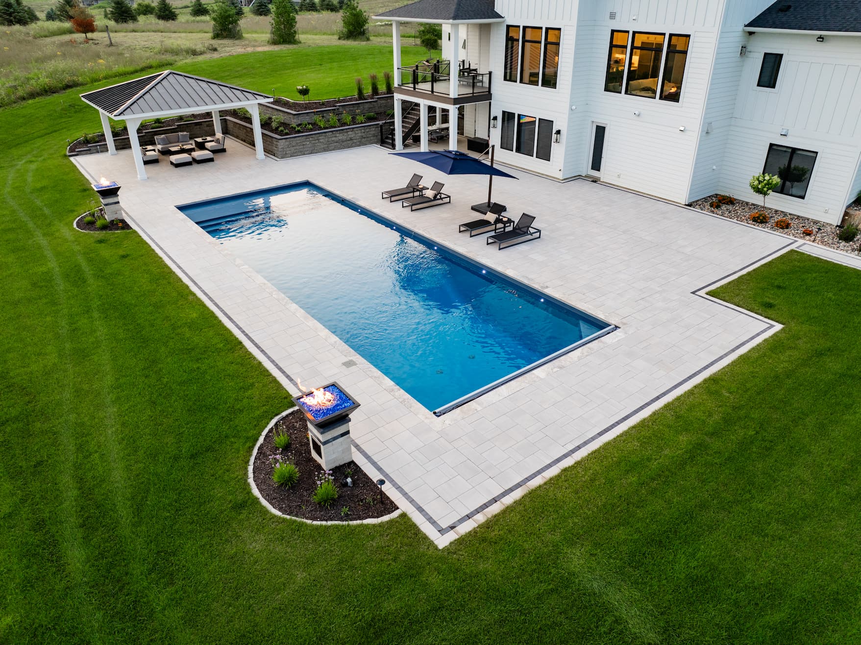 a large in-ground pool surrounded by a lush green yard