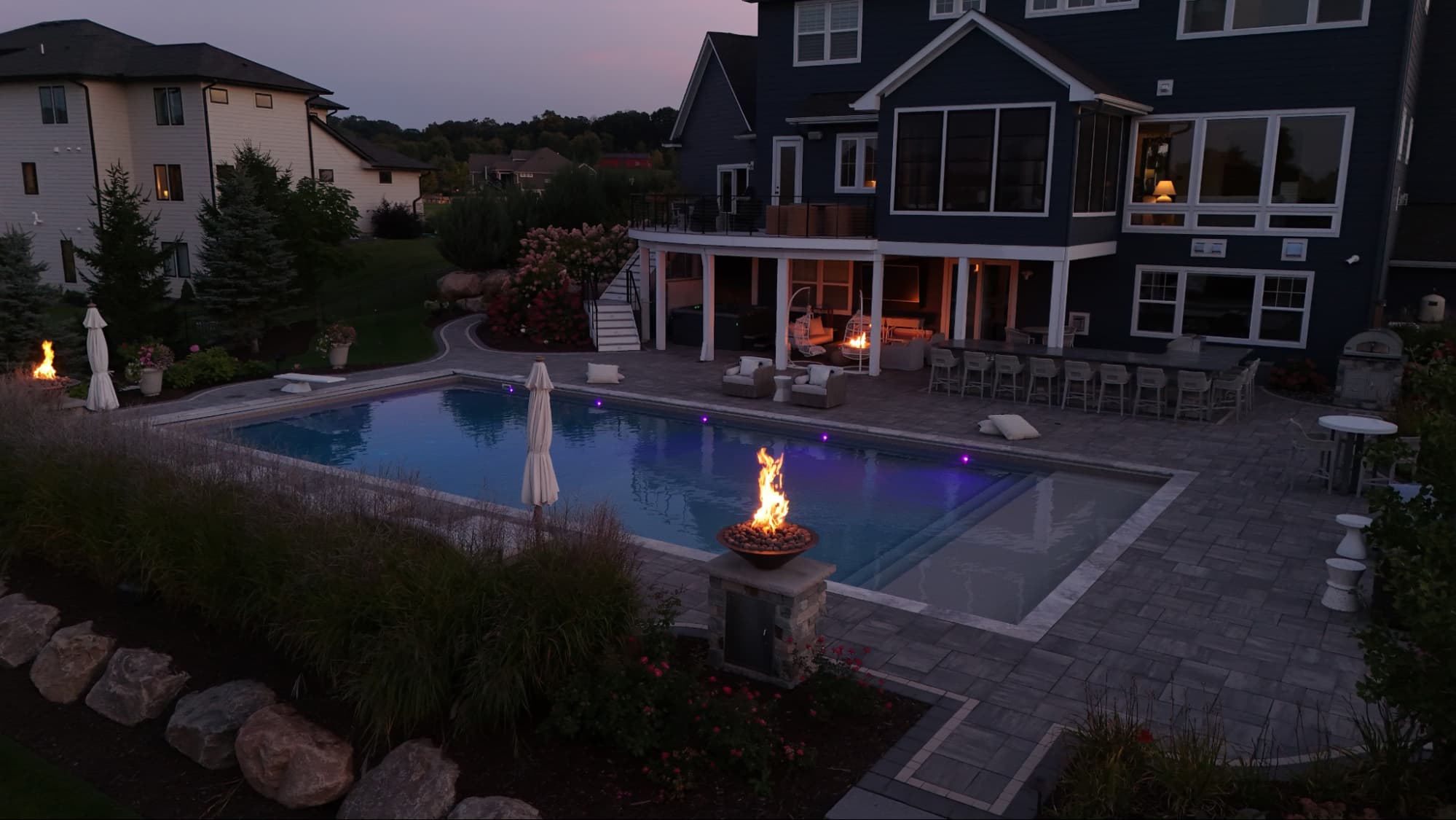 a pool in the evening, surrounded by fire features